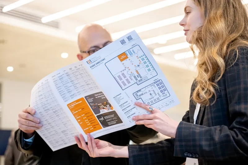 Two attendees reviewing the 121 Mining Investment event directory together