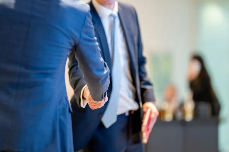 Two mining industry professionals shaking hands at a 121 Mining Investment event