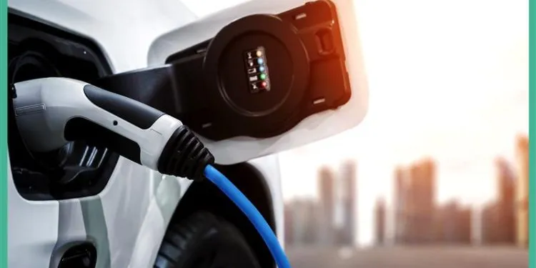 Electric vehicle connected to a charging point, with a city skyline in the background