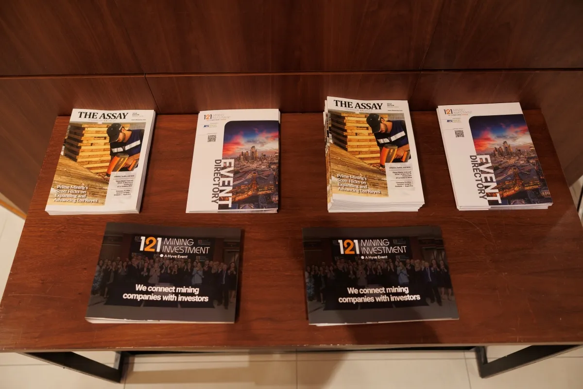 121 Mining Investment brochures, event directories and The Assay magazines displayed on a table
